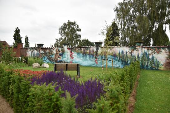 Kleurrijke rouwtuin met zitbank en graffitimuur